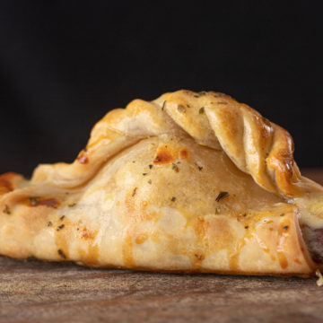 Empanada argentina assada inteira, com a borda trançada fechada à mão