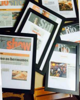 Matérias de jornal e revista sobre a Las Empanadas, emolduradas na parede da loja